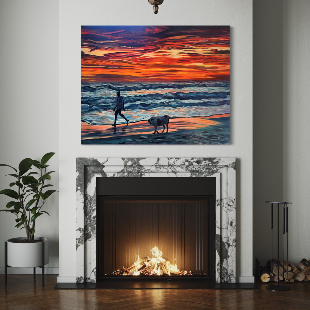 The artwork 'The Journey' by Claudia Robles-Gil depicts a figure walking with a dog along a beach at sunset. Vibrant orange and red hues dominate the dramatic sky, contrasting with deep blue ocean waves. The silhouetted forms are set against a luminous shoreline where water meets sand, painted in oil and acrylic on a 48x60 inch canvas, creating a striking atmospheric seascape.