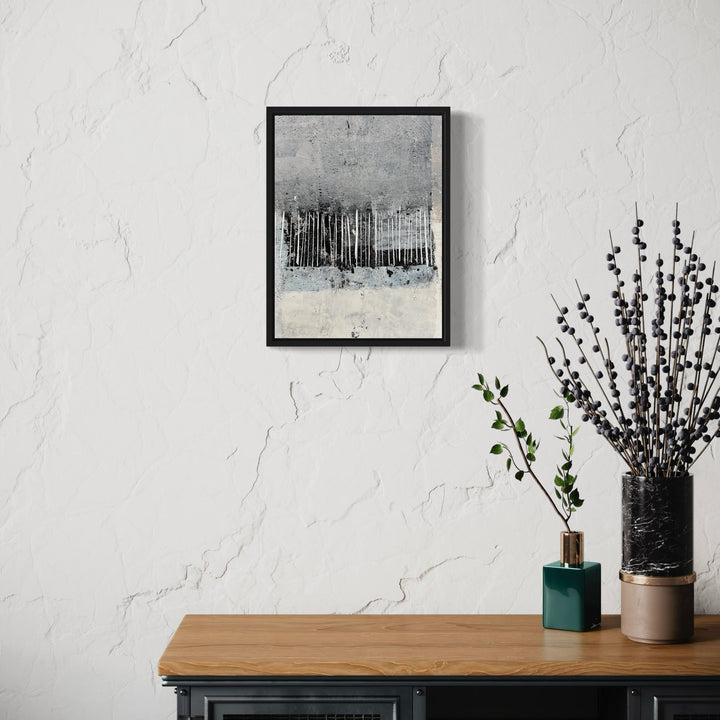 The artwork 'The Next Hurricane' by Karen L. Burns features a stark monochromatic composition depicting vertical lines resembling a forest silhouette against a misty gray background. The abstract acrylic piece combines textural elements with a minimalist approach, creating a moody atmospheric landscape in black, white, and gray tones, framed in sleek black, measuring 16x12 inches.
