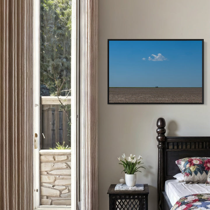 The artwork 'The Soul Cloud' by Dennis Maida captures a minimalist landscape photograph featuring a vast brown plowed field stretching to the horizon under a brilliant azure blue sky. A single pristine white cloud floats above, creating a striking contrast against the endless expanse, framed in black - by Dennis Maida