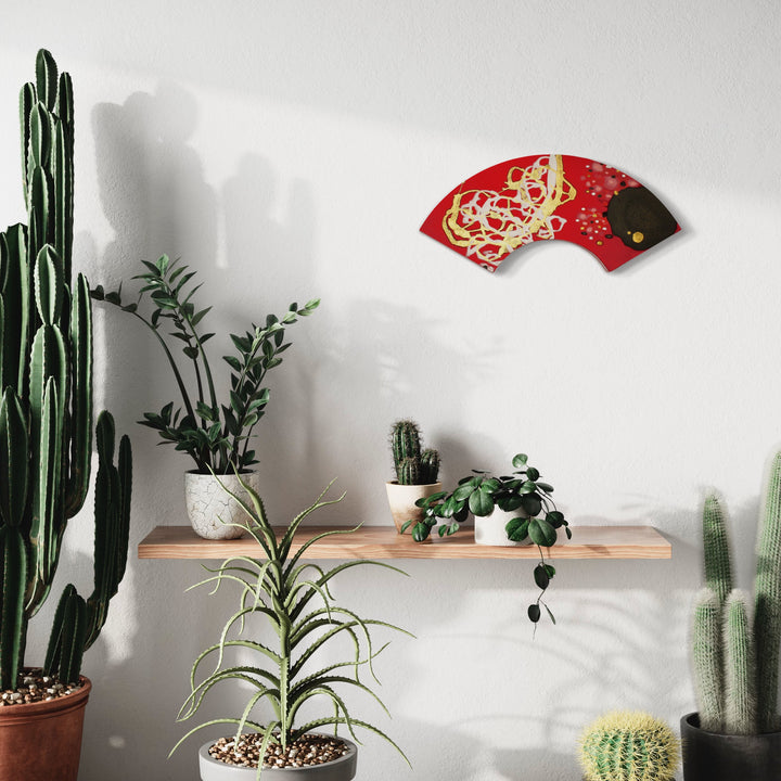 The artwork 'Tonglen' by Eric Jiaju Lee features a vibrant red fan-shaped silk painting adorning a minimalist white wall, complemented by a collection of desert plants including tall cacti, succulents, and trailing greenery arranged on a wooden floating shelf. Abstract golden swirls dance across the red silk canvas, creating an elegant Asian-inspired design. - by Eric Jiaju Lee
