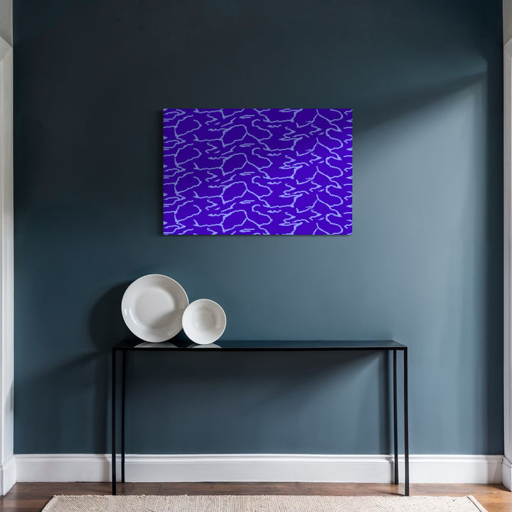 WATER by Harold Herb features an abstract composition of fluid, irregular silver lines on a deep blue background. Positioned above a minimalist black console table holding two white ceramic plates, the artwork enhances the modern, tranquil ambiance of the room with its cool, reflective tones and organic patterning.