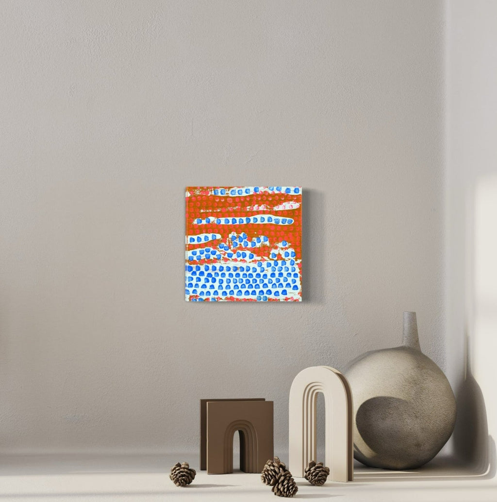The artwork 'Moving Right Along' by Taylor Binda features vibrant orange and bright blue abstract patterns. A series of dotted textures and linear elements create a dynamic composition on a wood panel. The blue dots form a wave-like pattern against the orange background, suggesting movement and flow. Painted in acrylic, this 10x10 inch contemporary piece combines geometric and organic elements. By Taylor Binda.