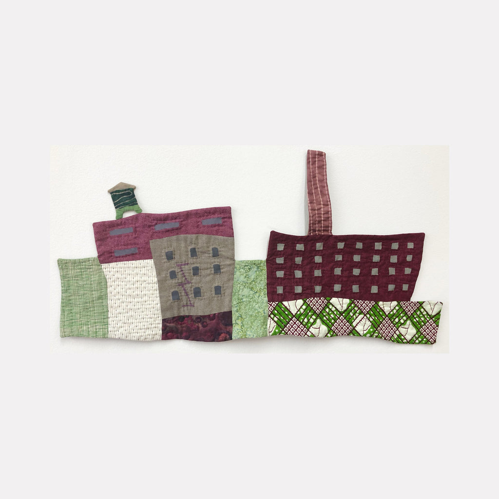 Cityscape (Shades of Green and Plum) by Ann Cofta features an abstract urban landscape rendered in fabric art. Geometric buildings in plum, grey, and sage green are quilted with textural stitching. The composition includes architectural elements like chimneys and windows, set against a cream background, showcasing a modern textile interpretation of city architecture.