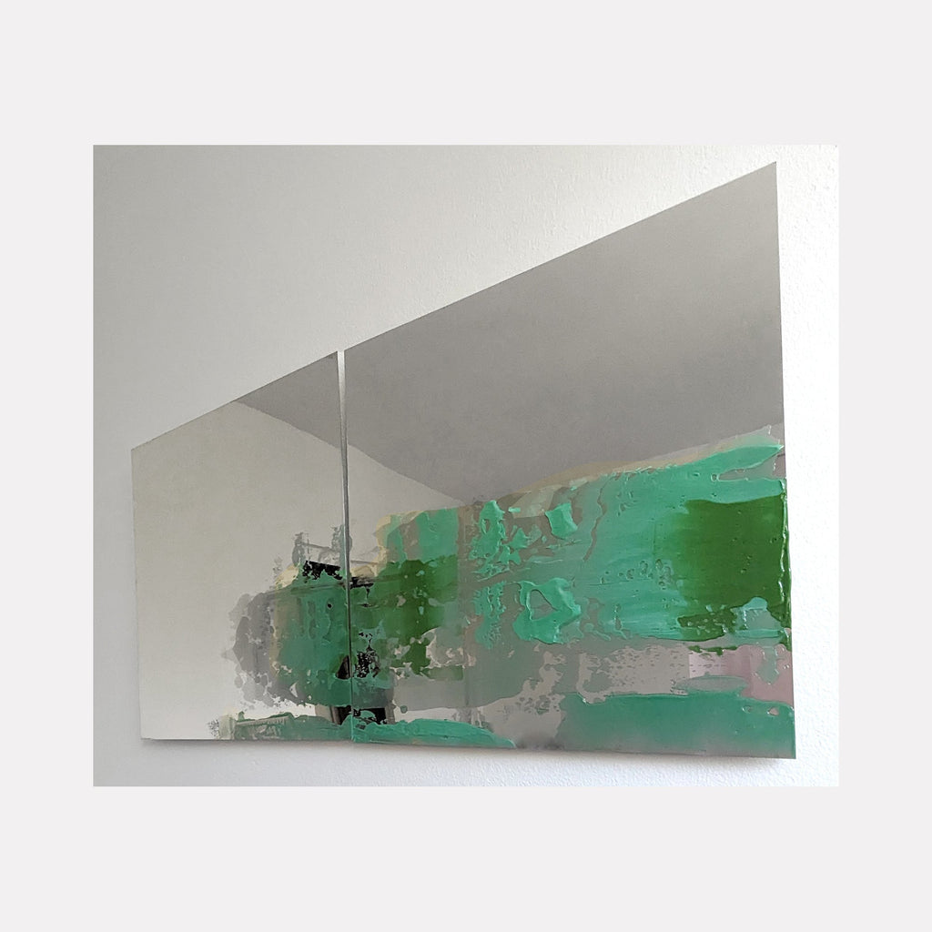The artwork 'Fragmented' by Sofia Echa features bold abstract strokes in vibrant emerald green and misty gray tones painted across a reflective stainless steel surface. The composition shows dynamic brushwork creating a horizontal movement, with textural acrylic elements merging against the metallic background, sized 24x48 inches.