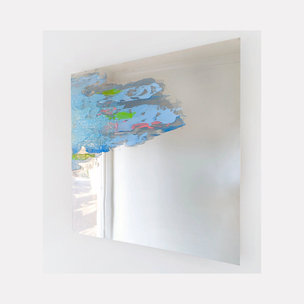 The artwork 'In Flux' by Sofia Echa features ethereal blue and green brushstrokes floating across polished stainless steel. Abstract forms reminiscent of clouds or water droplets create movement in the upper portion, contrasting with the reflective metallic surface. The 24x24 inch acrylic painting demonstrates a dynamic interplay between transparent colors and mirror-like material by Sofia Echa.