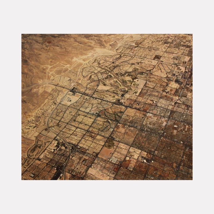 The artwork 'Over Las Vegas' by Christopher Blyth captures an aerial view of Las Vegas, rendered in warm sepia tones on oil and linen. The painting depicts the city's distinctive grid pattern, urban sprawl, and desert landscape, with intricate details of streets, buildings, and developments transitioning into untouched desert terrain. Size: 73x86 inches by Christopher Blyth.