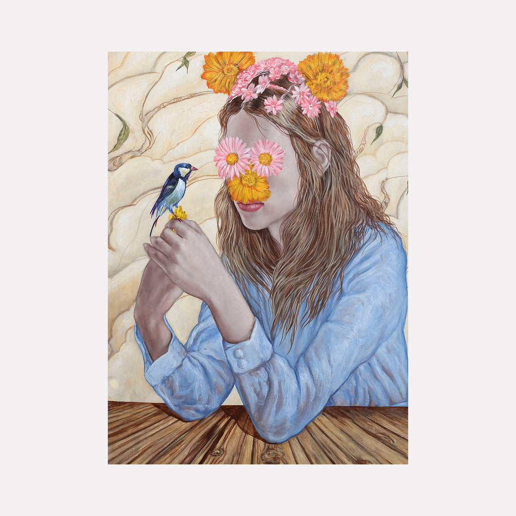 The artwork 'The Bird' by Carlos Gamez de Francisco features a surreal composition depicting a figure in a light blue button-up shirt, adorned with a crown of vibrant orange and pink flowers. A small blue and yellow bird perches delicately on the figure's hand against a cream-colored background with flowing organic patterns and wooden table surface. Acrylic on canvas, 28x28 inches.