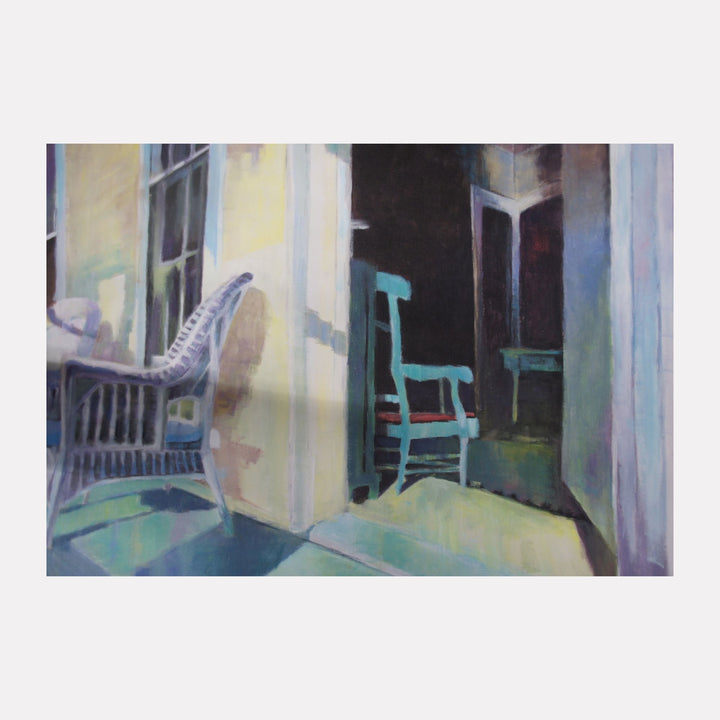 Chairs by Kristin Stashenko depicts a softly lit interior scene with a wicker chair bathed in cool light and a teal wooden chair casting shadows in a dimly lit room. The composition captures a quiet, introspective moment with subtle contrasts and peaceful tones that evoke calm and stillness.