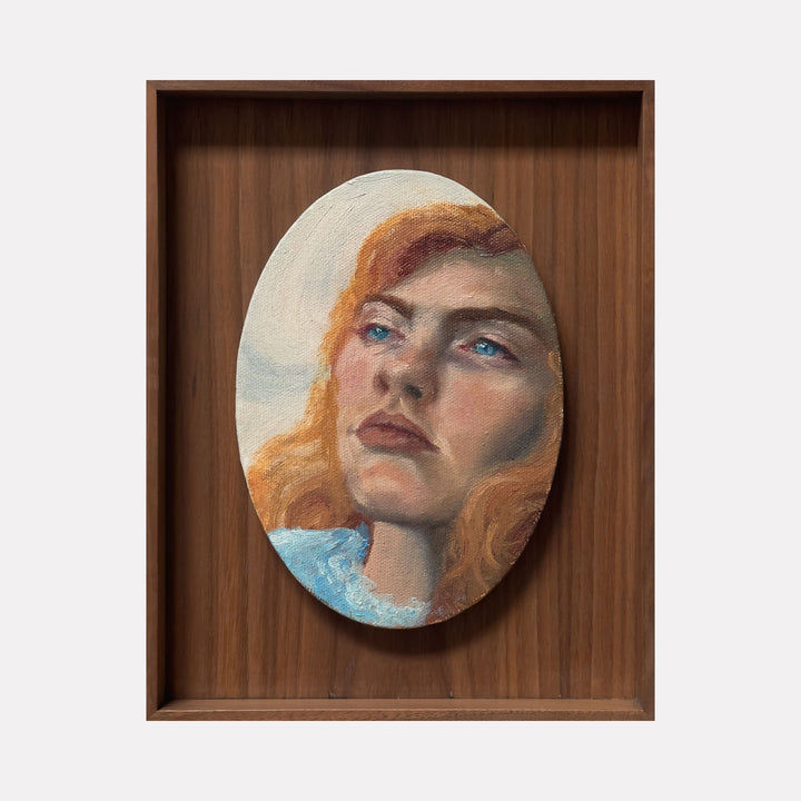 The artwork 'Dolly' by Jillian Shea features an oval oil painting set in a custom wooden frame. The composition captures an upward gaze against a soft blue sky background. Vibrant copper-toned hair frames the ethereal portrait, showcasing masterful oil painting techniques with rich textures and luminous skin tones on a 9.5 x 7.5 inch canvas.