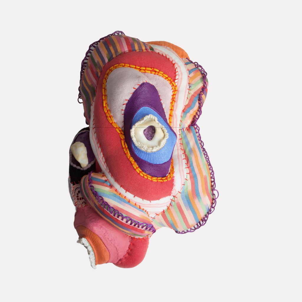 Foramina by Hanna Washburn features a vibrant textile sculpture combining layered fabric in bold stripes and solid colors with intricate stitching. The organic, abstract form blends soft textures and bright hues, evoking a playful yet thought-provoking sense of depth and tactile complexity.