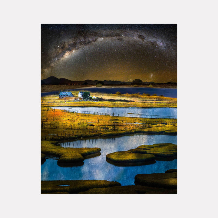 Stand #4 by Gordon Saperia depicts a luminous rural landscape with reflective waterways winding through golden fields, a farmhouse nestled amidst serene hills, and a vast starry sky arching above, blending tranquil natural beauty with celestial wonder in this Curina art piece.