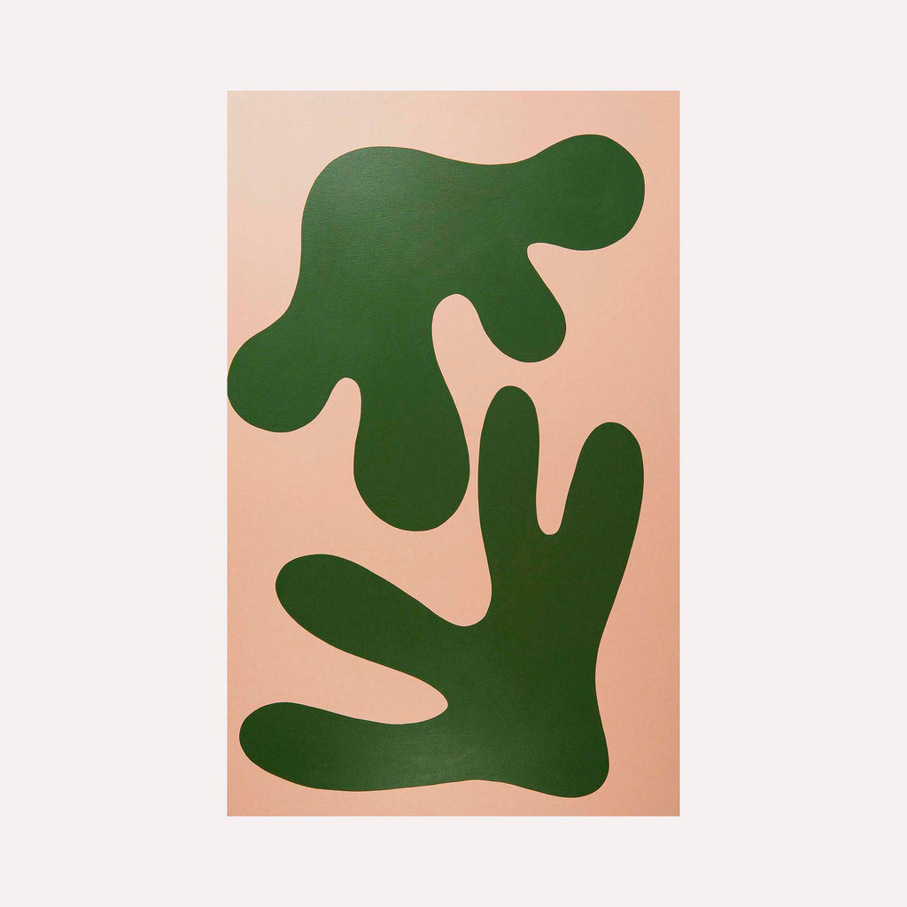 The artwork 'STAGHORN II' by Shadia Sabagh features bold organic shapes in deep forest green against a soft blush pink background. The abstract composition displays two flowing, curved forms reminiscent of staghorn fern fronds, created with clean lines and flat colors in acrylic on canvas, measuring 30 x 49 inches.