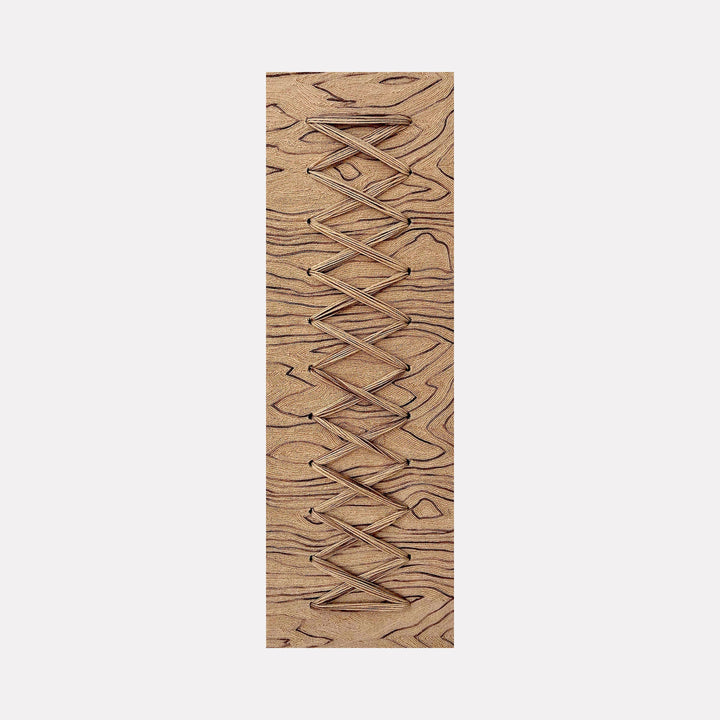 The artwork "Cross Stitch" by Quynn Douglas Dale features a rectangular wooden panel with natural grain patterns in warm brown tones. The piece showcases an intricate geometric crisscross design carved into the surface, evoking minimalist and abstract styles similar to the precision and texture found in works by Agnes Martin. The tactile quality emphasizes craftsmanship and organic materiality.