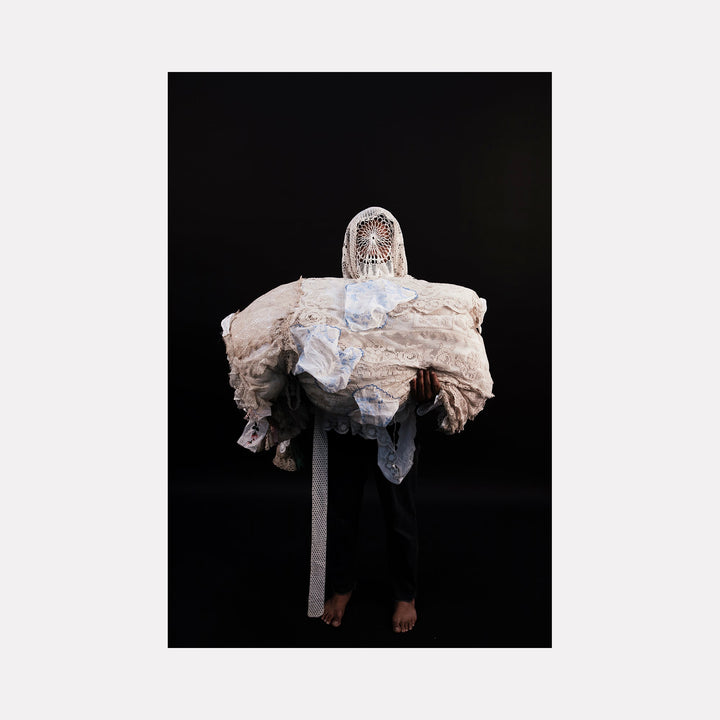 The artwork "080A8567" by Eunice Pais depicts a figure draped in textured, layered fabrics combining lace and delicate white cloth, obscuring the face with an intricate circular woven element. The composition offers a haunting, sculptural presence reminiscent of Magdalena Abakanowicz’s textile installations and the conceptual portraiture of Cindy Sherman.