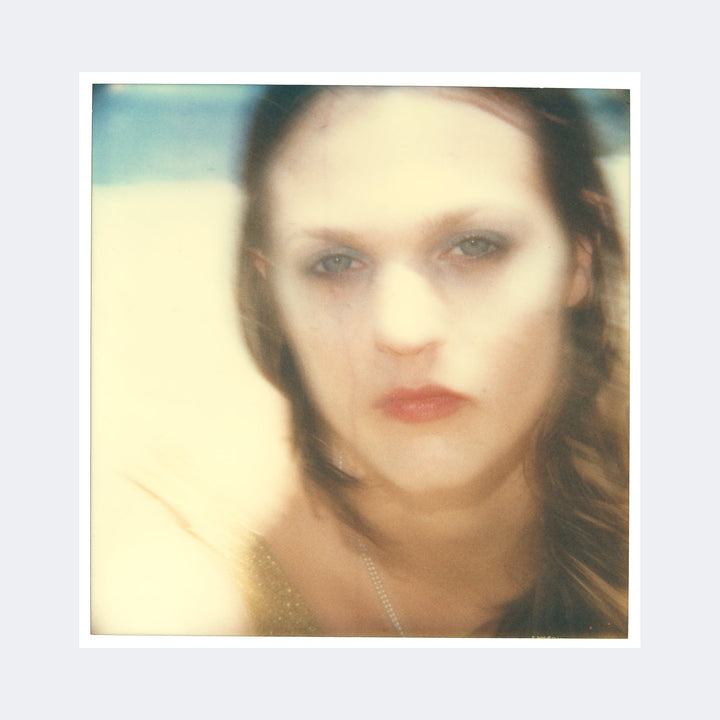 The artwork "Tears in the Rain (Beachshoot) 1448" by Stefanie Schneider features a soft-focus, ethereal portrait of a woman with blurred facial features and muted tones. The hazy texture and dreamlike quality evoke the style of photographers like Nan Goldin and the painterly softness of Gerhard Richter’s blurred portraits, combining cinematic warmth with impressionistic light.