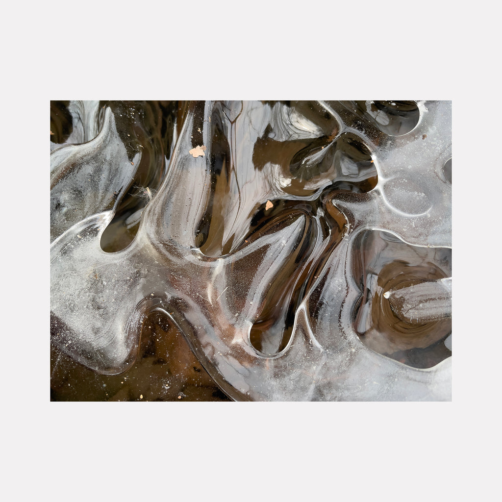 The artwork "Ice 1" by Molly Heron presents an abstract interplay of translucent icy forms with flowing contours against a dark, earthy background. The smooth, glass-like textures and organic shapes evoke the meditative abstraction of Agnes Martin and the fluid naturalism found in works by Hiroshi Sugimoto.