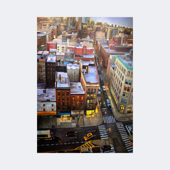 The artwork "Angels Over Manhattan" by Regina Miele depicts a vibrant aerial view of a New York City street corner at dusk, with detailed architectural forms and illuminated windows. The painting features rich earth tones, soft golden lighting, and a realistic yet atmospheric style reminiscent of Edward Hopper’s urban scenes and the detailed cityscapes of Richard Estes.