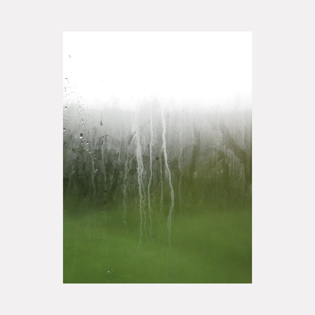 The artwork "Eyeries Conservatory #1" by Ann Tracy features a misty, abstract view through a rain-covered glass pane, with delicate water streaks running vertically. The blurred green and white hues evoke a serene, ethereal atmosphere reminiscent of the subtle textures and mood found in works by J.M.W. Turner and Mark Rothko.