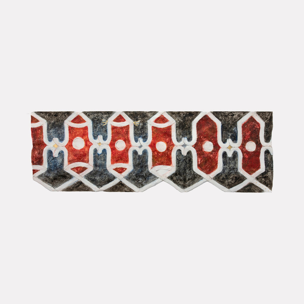 The artwork "Atrium East" by Adina Andrus features a horizontal band of interlocking geometric shapes in deep reds, muted blues, and earthy blacks framed by crisp white outlines. The textured surface and repetitive pattern evoke a tribal, woven textile aesthetic reminiscent of mid-century modern abstraction and the graphic compositions of Frank Stella and Ad Reinhardt.