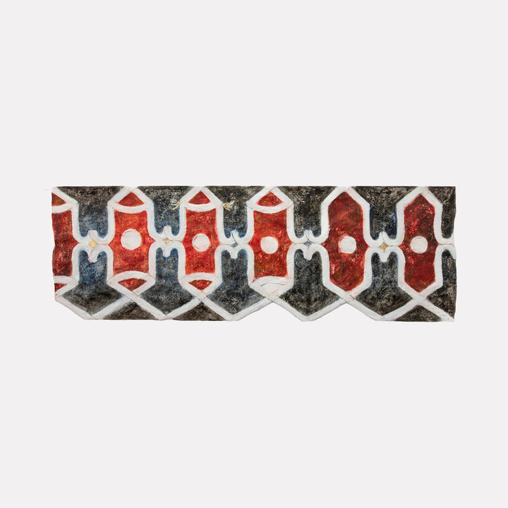 The artwork "Atrium East" by Adina Andrus features a horizontal band of interlocking geometric shapes in deep reds, muted blues, and earthy blacks framed by crisp white outlines. The textured surface and repetitive pattern evoke a tribal, woven textile aesthetic reminiscent of mid-century modern abstraction and the graphic compositions of Frank Stella and Ad Reinhardt.