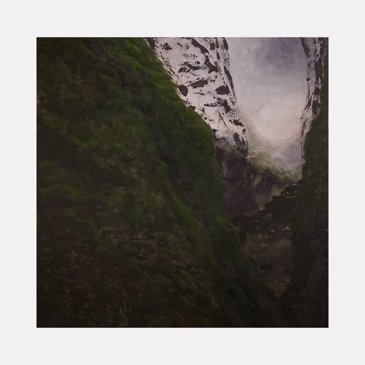 The artwork "Invisible Mountains" features towering, shadowed mountain forms covered partially with dark green moss and textured rock surfaces, blending into a misty, muted gray sky. The scene evokes a mysterious, ethereal atmosphere with soft light filtering through the mountain crevices. Art by Anne Cherubim.