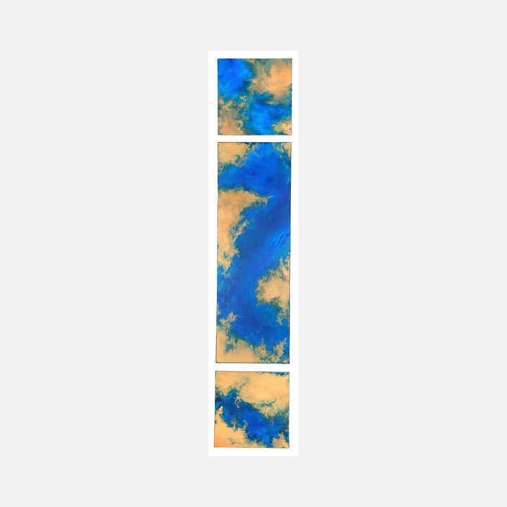 The artwork "Between Worlds" features a vertical triptych with abstract forms in vibrant blue and warm tan hues, blending fluid textures that evoke a sense of movement and depth. The piece combines organic shapes and layered brushstrokes creating a dynamic contrast between cool and earthy tones by Anne Cherubim.