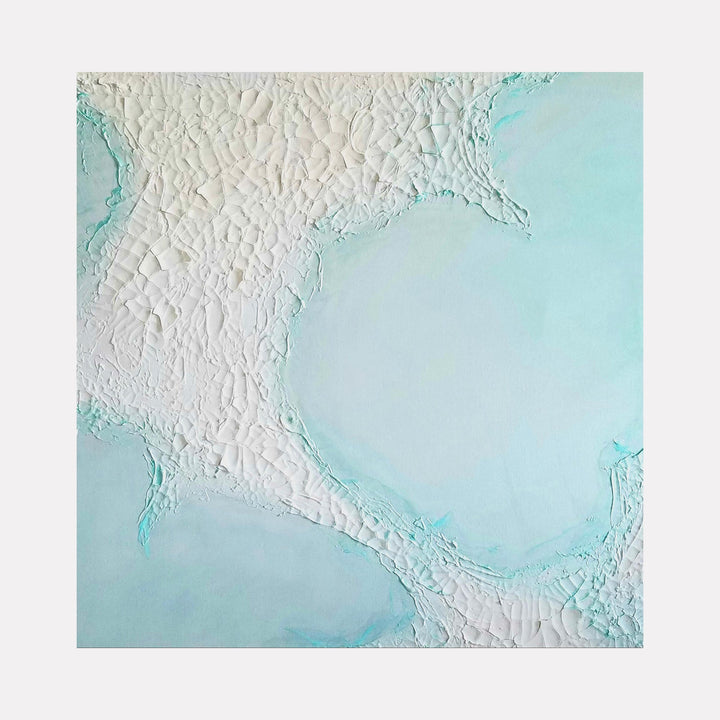The artwork "Where White Sands Drift" features a textured surface with cracked, white sandy patterns blending into smooth, pale turquoise and aqua hues, creating an abstract coastal or desert impression. The piece highlights intricate, raised textures contrasting with soft, fluid color transitions. By Anne Cherubim.
