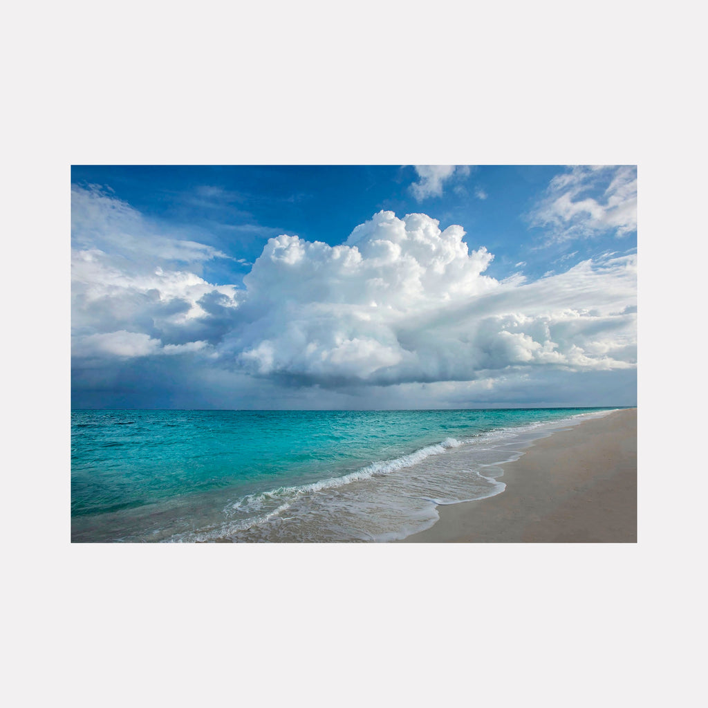 Caribbean Landscape by Steve Edson captures a tranquil beach scene with turquoise waters gently meeting a soft sandy shore under a vast sky filled with large, billowing clouds, evoking a serene and peaceful tropical atmosphere.