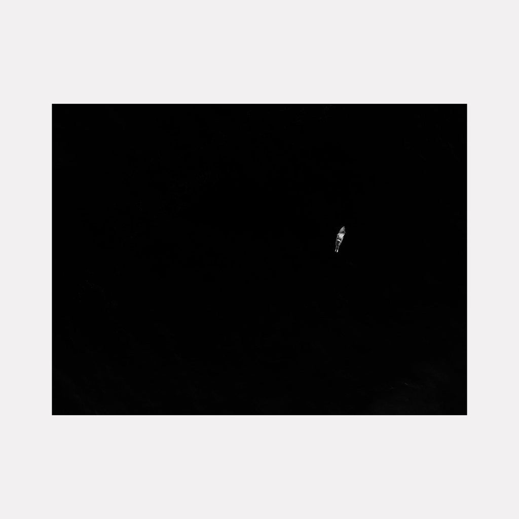 The artwork "Enough" features a minimalist composition dominated by deep black space with a small, solitary white shape near the center that evokes feelings of isolation and contemplation. The stark contrast and simplicity resemble elements of Kazimir Malevich’s Suprematism and Barnett Newman’s color field works. Dennis Maida.