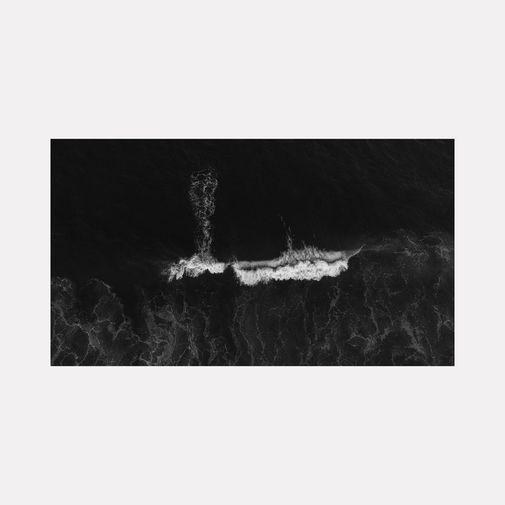 The artwork "Hold" by Dennis Maida features a monochromatic aerial view of ocean waves crashing and swirling, creating dynamic white foam patterns against a deep black sea background. The texture and contrast evoke the abstract styles of Gerhard Richter and the minimalism of Robert Motherwell. Dennis Maida.