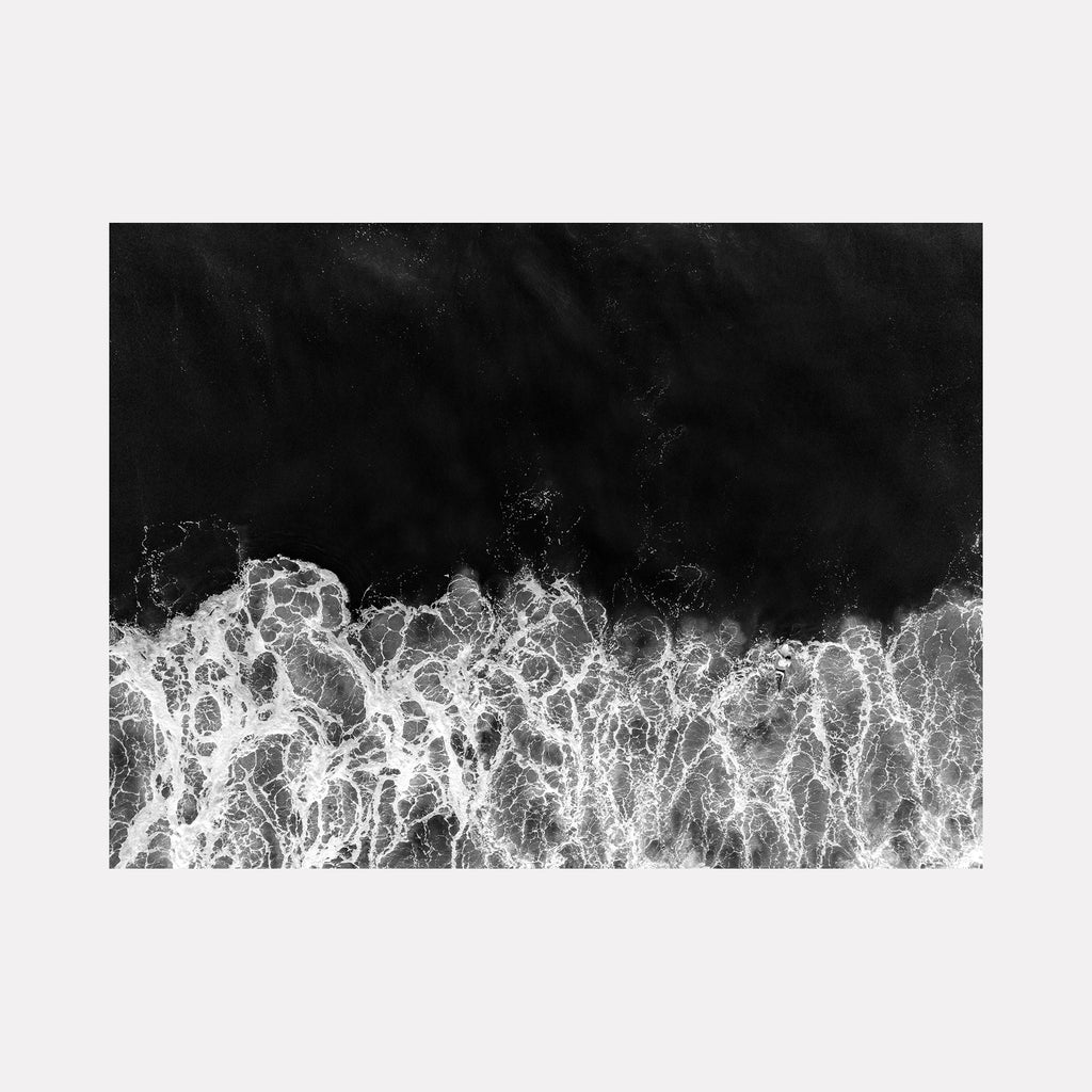 The artwork "Reentry" features a monochromatic aerial view of ocean waves crashing with intricate white foam patterns against a deep black sea background, reminiscent of the high-contrast style seen in Ansel Adams' photography and the abstract expressionism of Franz Kline. This textured, dynamic piece is by Dennis Maida.