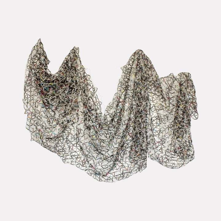 The artwork Fashion Textile 2005-2015 by Kate Rusek features a delicate, draped textile with an intricate geometric lattice pattern resembling interconnected triangles. The fabric appears translucent with subtle color variations beneath the surface, evoking a blend of modern minimalism and the structural abstraction found in works by Frank Stella and Agnes Martin.