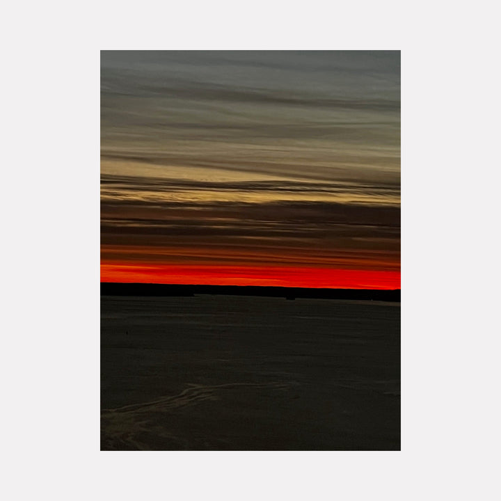 The artwork "Fire & Ice 1" by Starr Tucker-Ortega features a dramatic horizon with a stark contrast between deep fiery red and muted icy gray tones. The sky displays layered wispy clouds transitioning from warm orange and red near the horizon to cooler grays and blues above, evoking a serene yet intense natural landscape. Starr Tucker-Ortega