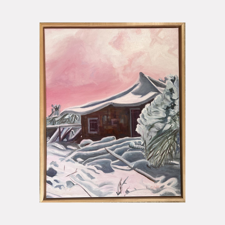 The artwork "Hobbit House 2" by Connie Falk showcases a serene winter cabin covered in thick snow under a soft pink sky. The painting features expressive brushstrokes and a blend of realism with impressionistic style reminiscent of Claude Monet’s atmospheric landscapes. The wooden cabin and snow-covered trees create a tranquil, cozy scene.