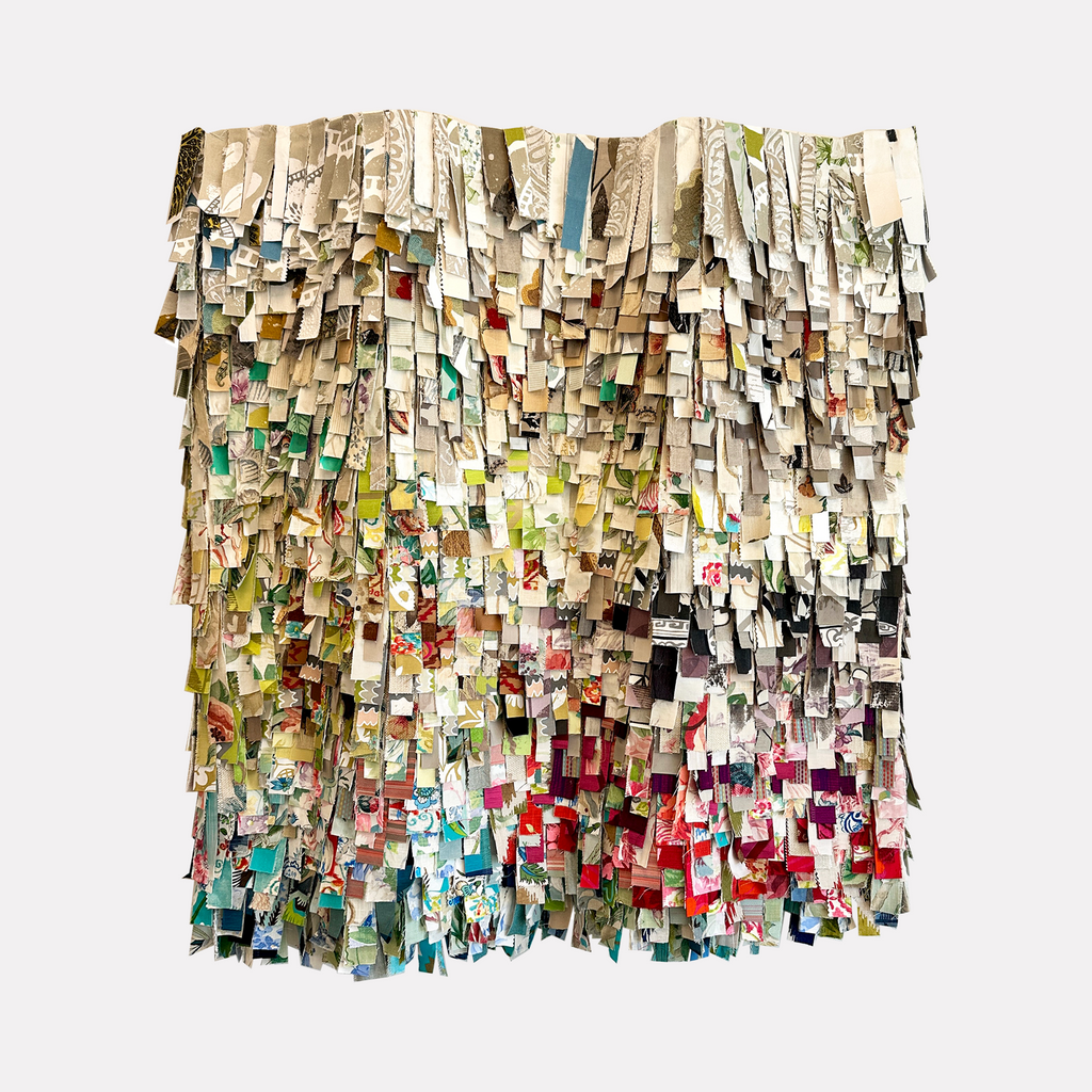 In the Fray by Shiri Phillips showcases a layered mosaic of cut fabric strips featuring a rich tapestry of soft neutrals, greens, reds, and blues. The textured, cascading arrangement evokes movement and depth, infusing a handcrafted, vibrant energy that elegantly blends pattern and color in a captivating abstract form.