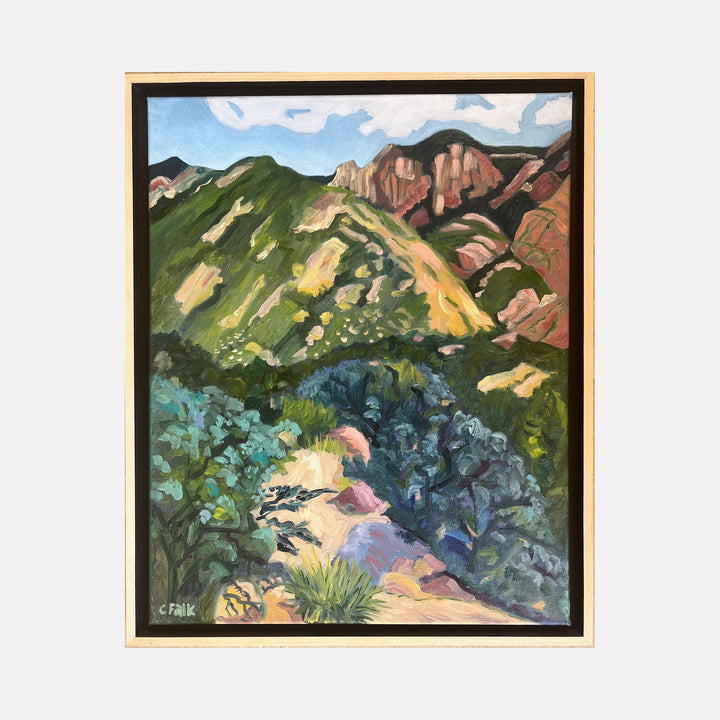 The artwork La Cueva 1 by Connie Falk depicts a vibrant mountain landscape with layered ridges in earthy greens, browns, and yellows. The textured brushstrokes and bold color palette evoke the expressive style of early 20th-century painters like Georgia O’Keeffe and the structure recalls the organic forms in Cézanne’s landscapes.