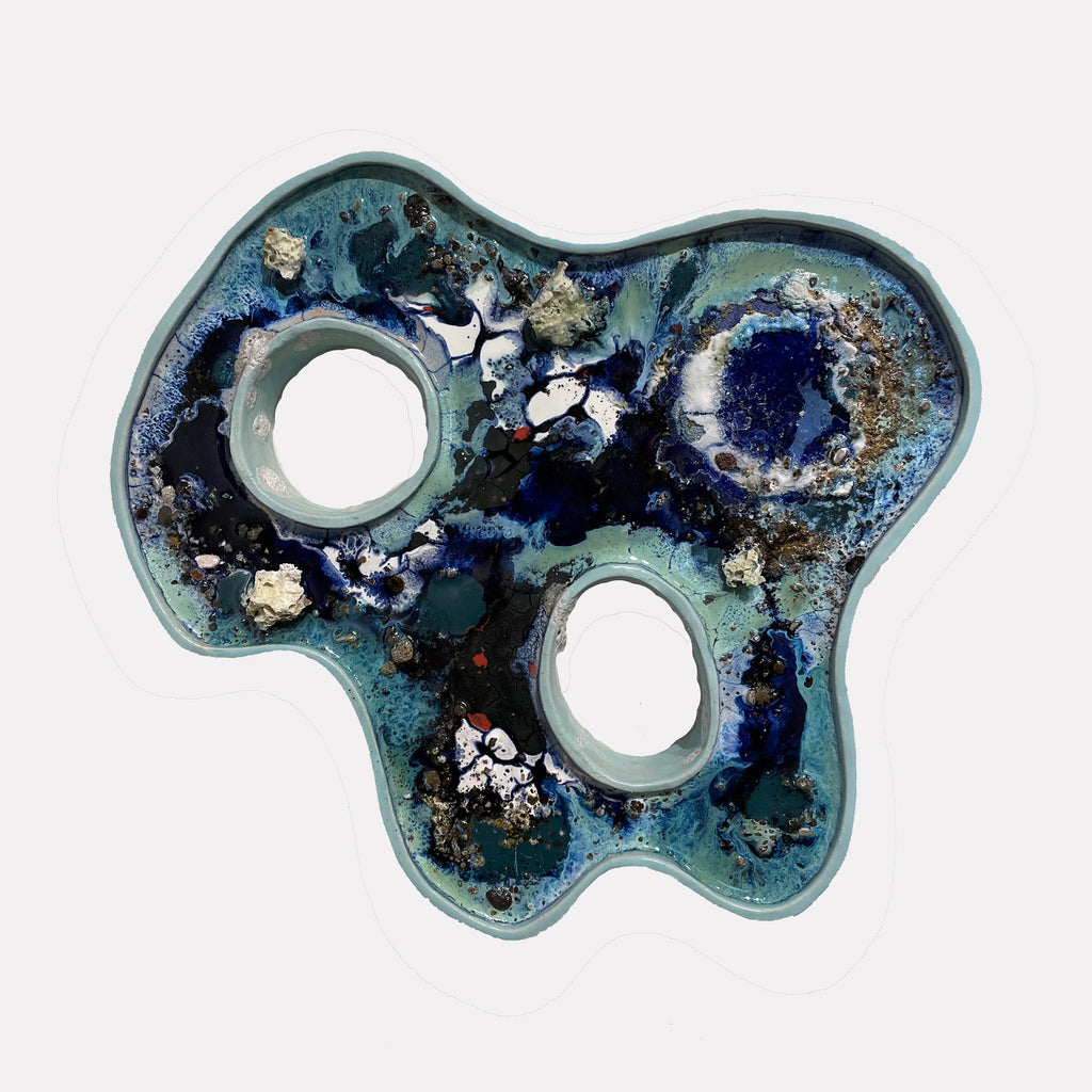 The artwork "Caribbean" by Lisa S. Truax showcases an irregular, organic form with two prominent hollow circular spaces, rendered in deep blues, teals, and hints of black and white. Textured layers and speckled accents evoke the natural fluidity and depth reminiscent of the atmospheric abstractions of Helen Frankenthaler and the tactile surfaces of Gerhard Richter.