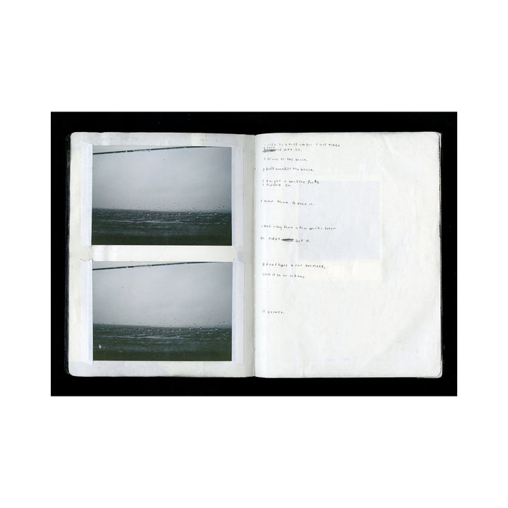 The artwork "Lost Car" features a minimalist open book displaying two small, dark, and moody photographs of a vast, textured ocean under an overcast sky, alongside faint handwritten notes on a white page. The composition emphasizes stark contrast and quiet introspection. By Kelly McGovern.