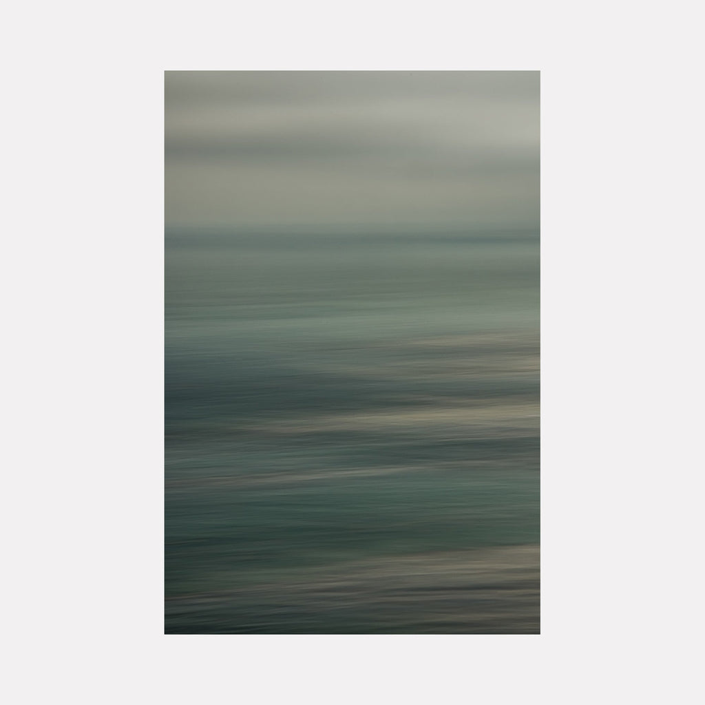 The artwork "Malaga Cove Sunrise" by Neil Shapiro features a serene, abstract seascape with soft horizontal brushstrokes in muted blues, grays, and hints of green. The piece evokes a sense of calm and peaceful motion, reminiscent of Mark Rothko’s layered color fields and the subtle atmospherics found in J.M.W. Turner’s seascapes.