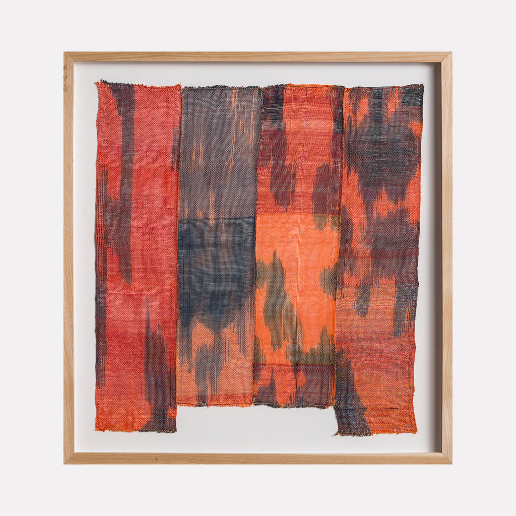 The artwork "Untitled #156" by Victoria Manganiello features a textured, woven fabric with vertical panels in varying shades of red, orange, and deep charcoal. The piece exhibits an abstract pattern with irregular, smoky patches, emphasizing a rough, tactile surface within a simple light wood frame.