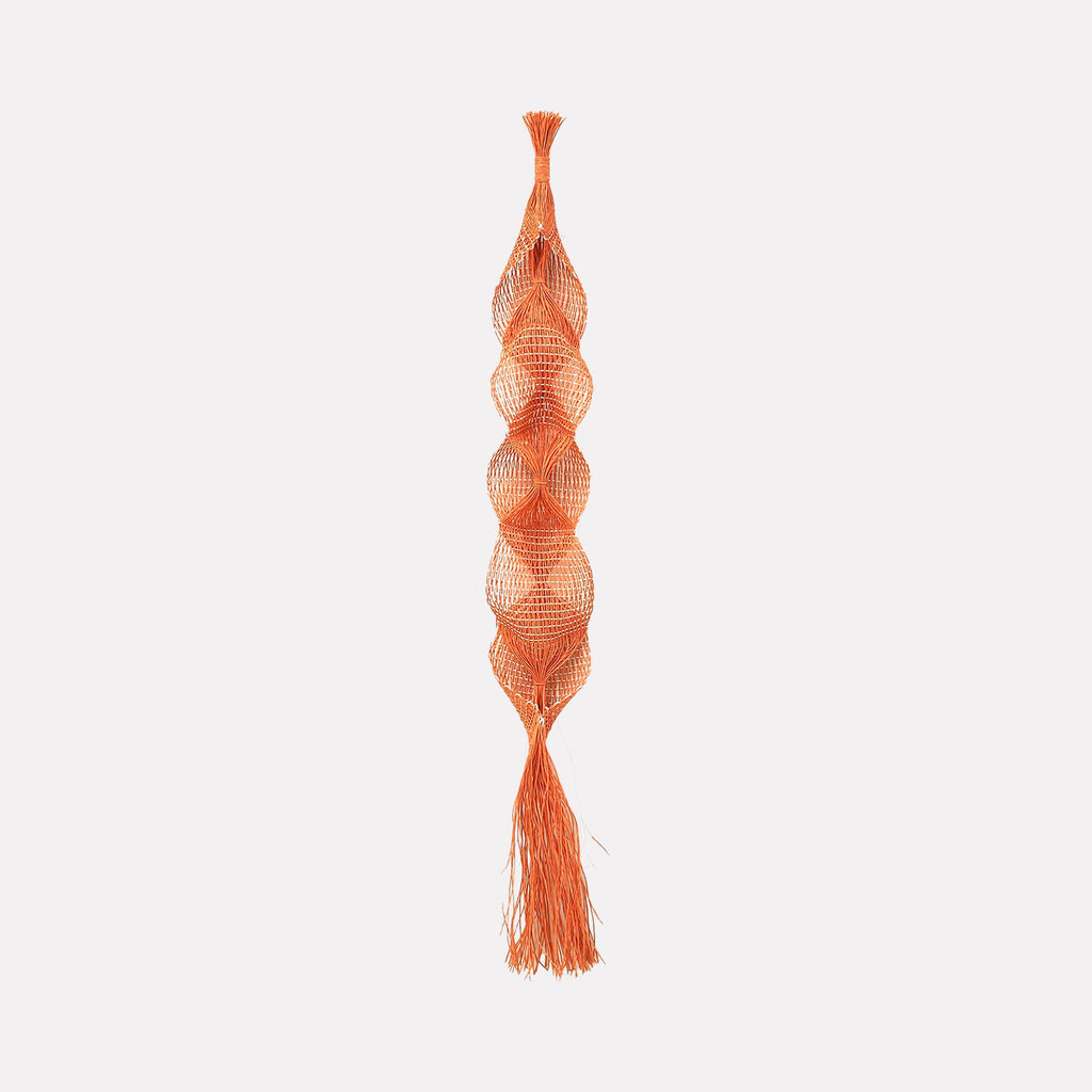 The artwork Lily Pendant by Morgan Hale features an elongated, intricate macrame design in warm terracotta orange. The pendant displays a series of symmetrical, diamond-shaped knots combined with rounded, bulbous textures reminiscent of mid-century modern craft. Its delicate fringe detailing at the bottom evokes natural fiber art inspired by the tactile qualities found in works by Sheila Hicks.