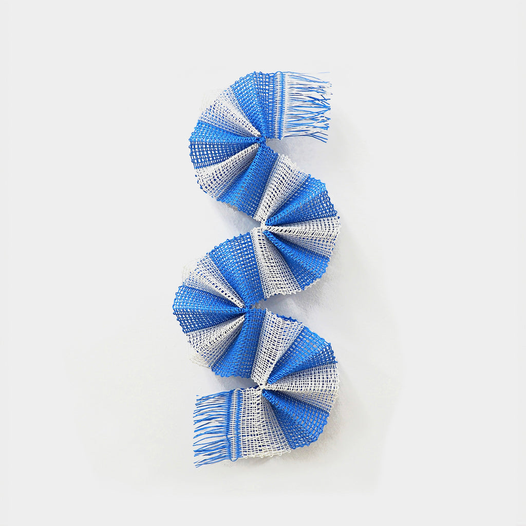 The artwork "Sky Curve" by Morgan Hale features a spiraling ribbon-like form composed of woven blue and white textured strips. Its fluid, twisting shape and interplay of color evoke the movement found in modernist sculptures and the textile works of Anni Albers, combining structure and softness in an elegant, minimalist style.