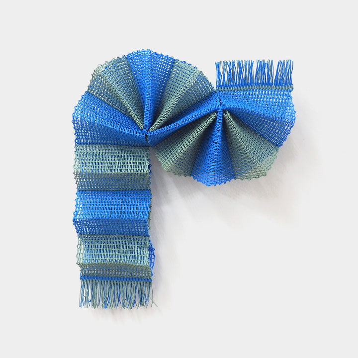 The artwork "Tree Tunnel" by Morgan Hale features an intricate arrangement of woven mesh fabric in vibrant blue and muted green tones, forming a dynamic, folded structure with repeated linear textures and a rhythmic play of light and shadow, reminiscent of the abstract textile works of Anni Albers and the sculptural forms of Ruth Asawa.