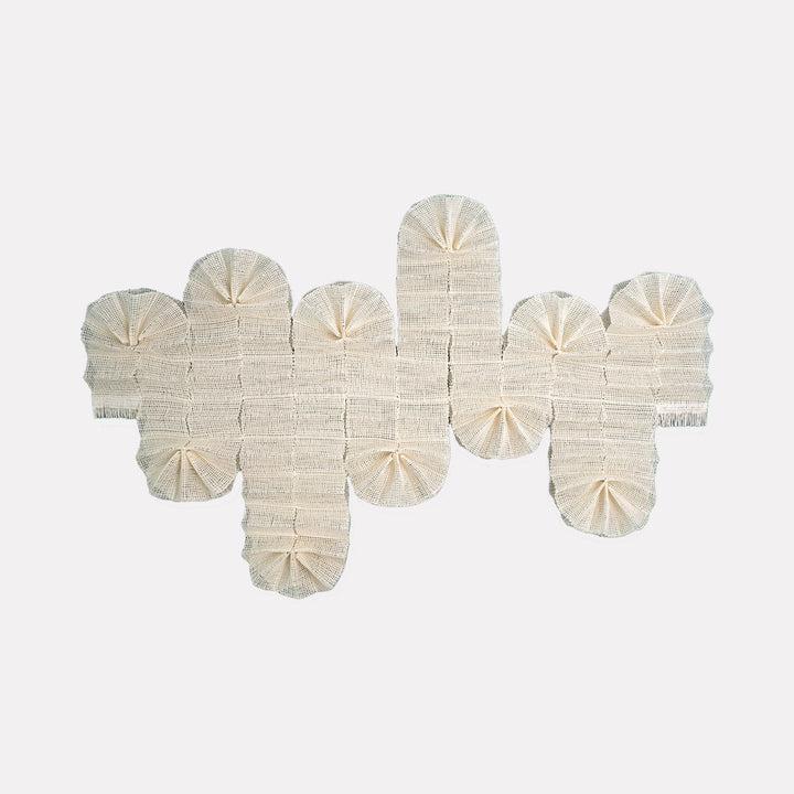 The artwork "Winter In The Air" by Morgan Hale features a monochromatic, textured textile composition in soft off-white tones. Its layered, rounded fan-like segments create a rhythmic pattern with subtle shadows, evoking a serene, minimalist landscape. The tactile, woven forms recall the organic abstraction of Eva Hesse and the subtle textural play of Agnes Martin.