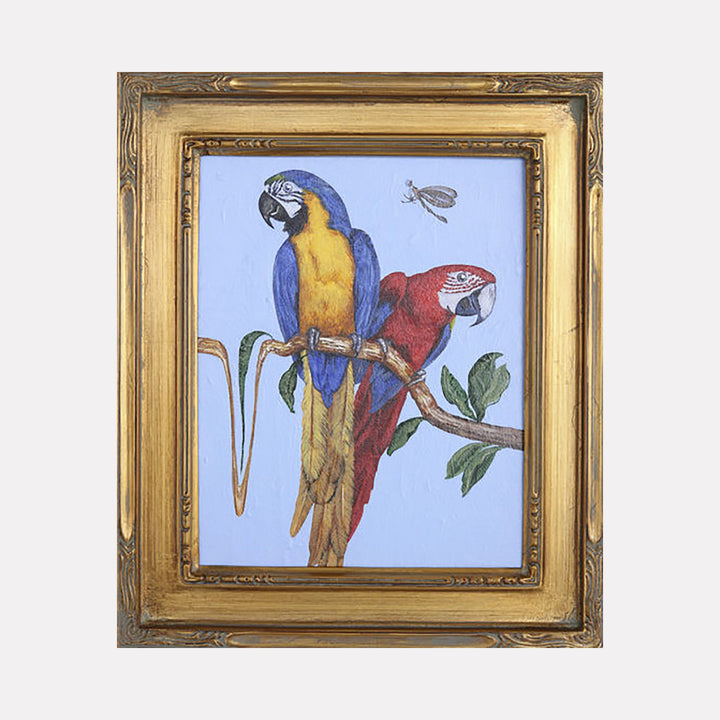 The artwork "New World Parrots" by Carlos Gamez de Francisco features two colorful parrots perched on a branch against a light blue background. One parrot displays vibrant blue and yellow feathers, while the other showcases rich red plumage. A dragonfly hovers nearby, enhancing the natural scene within an ornate gold frame.