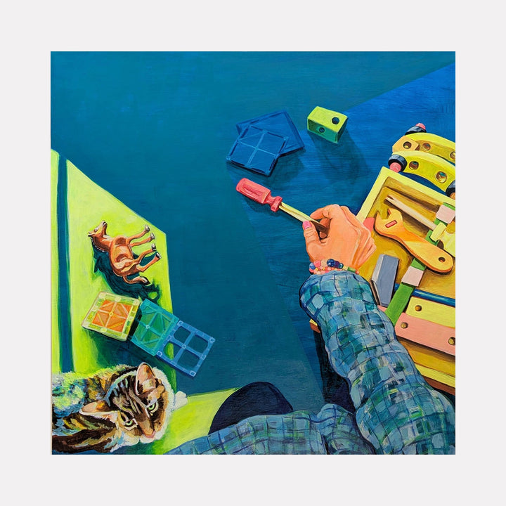 The artwork "Picking Up the Pieces" depicts a person’s hand holding a red screwdriver above a colorful wooden toolbox containing various tools, set against a deep blue background. A tabby cat rests nearby on a bright yellow surface alongside small toy blocks and a camel figurine. The style combines realism with subtle surrealist elements reminiscent of Edward Hopper’s attention to light and everyday scenes. Mary Younkin.