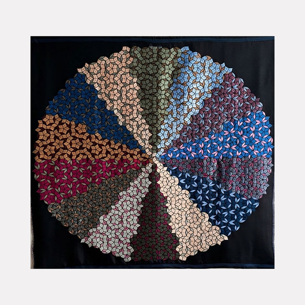 Quasicrystals (#R3) by Victoria Manganiello is a Curina art piece featuring a circular, quilt-like design segmented into geometric patterns in muted earth tones, blues, and reds, creating a harmonious, textured mosaic that evokes complexity and structured beauty.