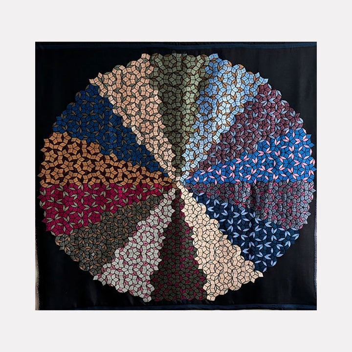 Quasicrystals (#R3) by Victoria Manganiello is a Curina art piece featuring a circular, quilt-like design segmented into geometric patterns in muted earth tones, blues, and reds, creating a harmonious, textured mosaic that evokes complexity and structured beauty.