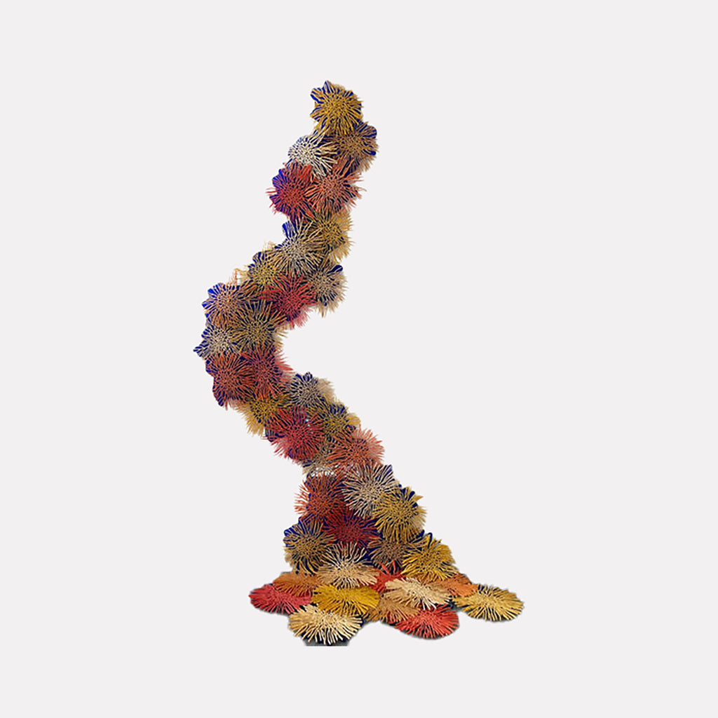 The artwork "RUSH" by Nora Chavooshian features a dynamic, vertical arrangement of textured, spiky floral shapes in warm tones of red, yellow, orange, and purple against a light background, creating a sense of organic movement and depth. The piece emphasizes intricate detail and vibrant color contrast. Nora Chavooshian.
