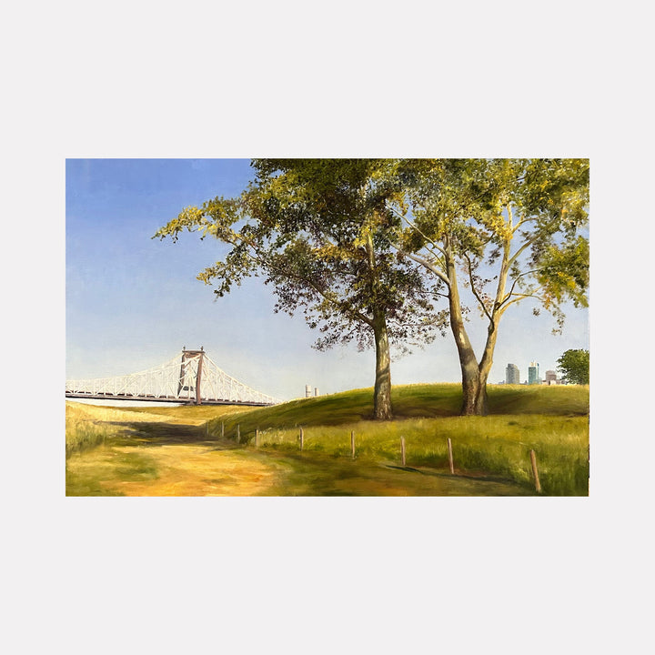 The artwork "Roosevelt Island Oasis" by Jessica Ziegler depicts a serene landscape featuring a softly lit suspension bridge in the background, lush green trees with detailed foliage, and a gently curving dirt path under a clear blue sky. The style echoes the realism and atmospheric qualities found in the works of artists like Andrew Wyeth and Albert Bierstadt.